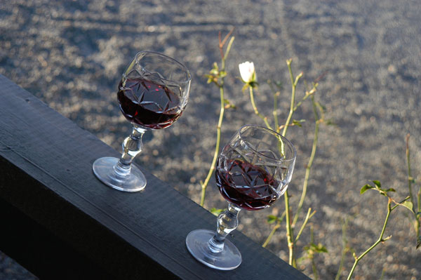 Two wine glasses with a white rose in background