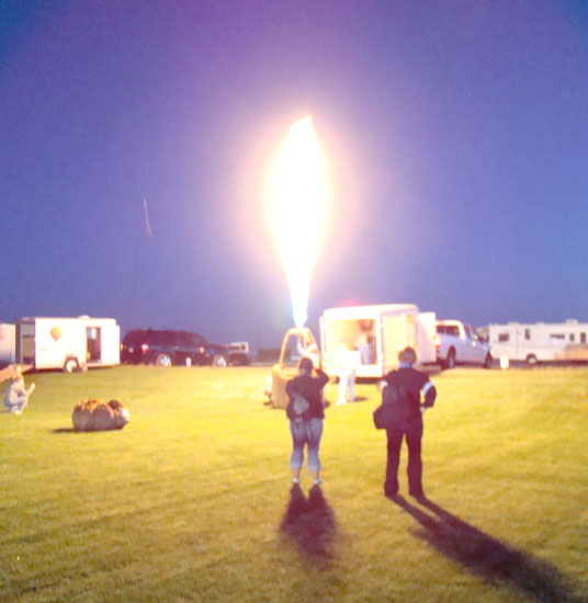 Hot air balloonists test the propane burner in the darkness before dawn.